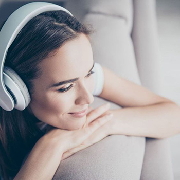 A woman is listening to a music with headphones